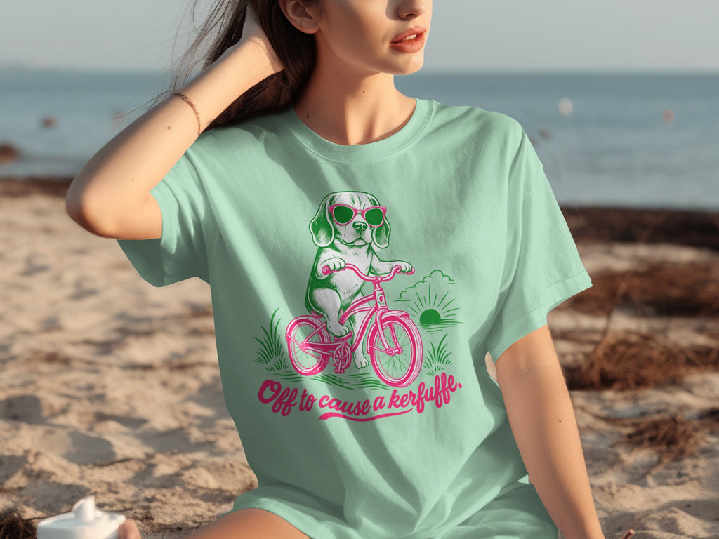 Mint t-shirt with a cartoon dog riding a bicycle, "Off to cause a kerfuffle" text.
