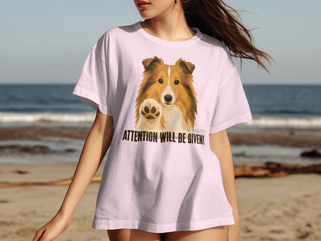 Light pink t-shirt featuring a Shetland Sheepdog raising its paw with text "ATTENTION WILL BE GIVEN!".