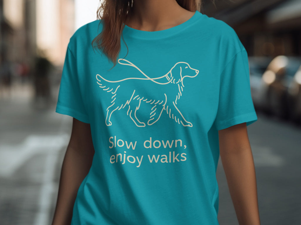 Teal t-shirt with white line drawing of a dog on a leash and text "Slow down, enjoy walks".