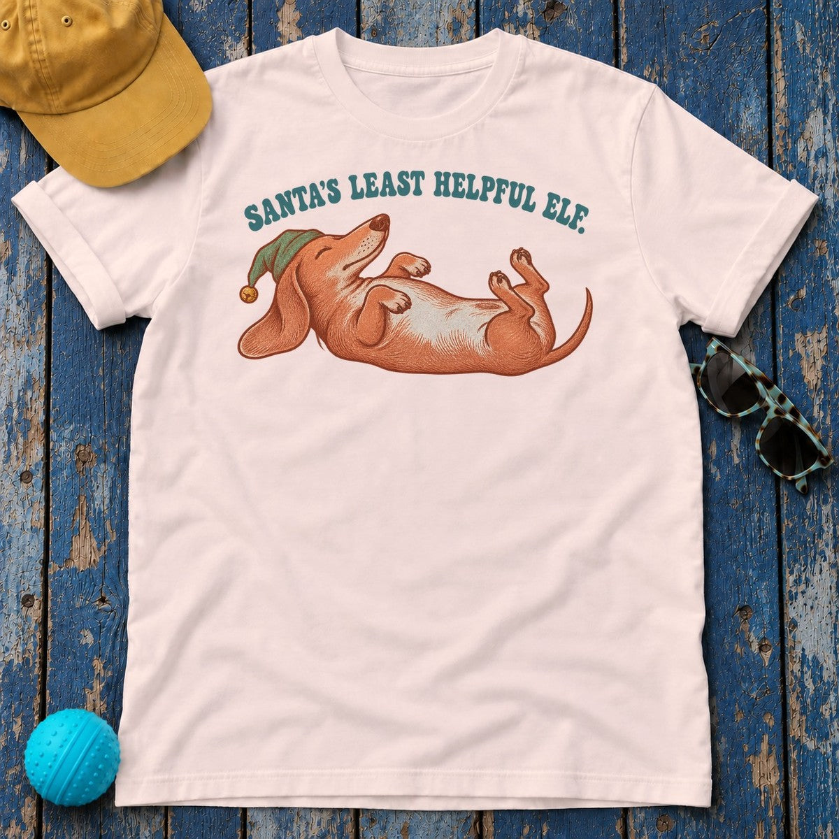 Santa's Least Helpful Elf Dachshund T-Shirt in Soft Pink - flat lay