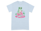 Light blue t-shirt with a dog in sunglasses riding a bicycle, text reads "Off to cause a kerfuffle."
