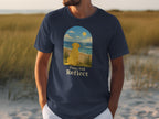 Dark blue t-shirt with a yellow dog looking at the ocean, text reads "Paws And Reflect".