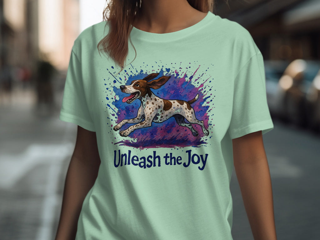Light green t-shirt with a running dog illustration and "Unleash the Joy" text.