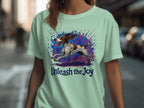 Light green t-shirt with a running dog illustration and "Unleash the Joy" text.