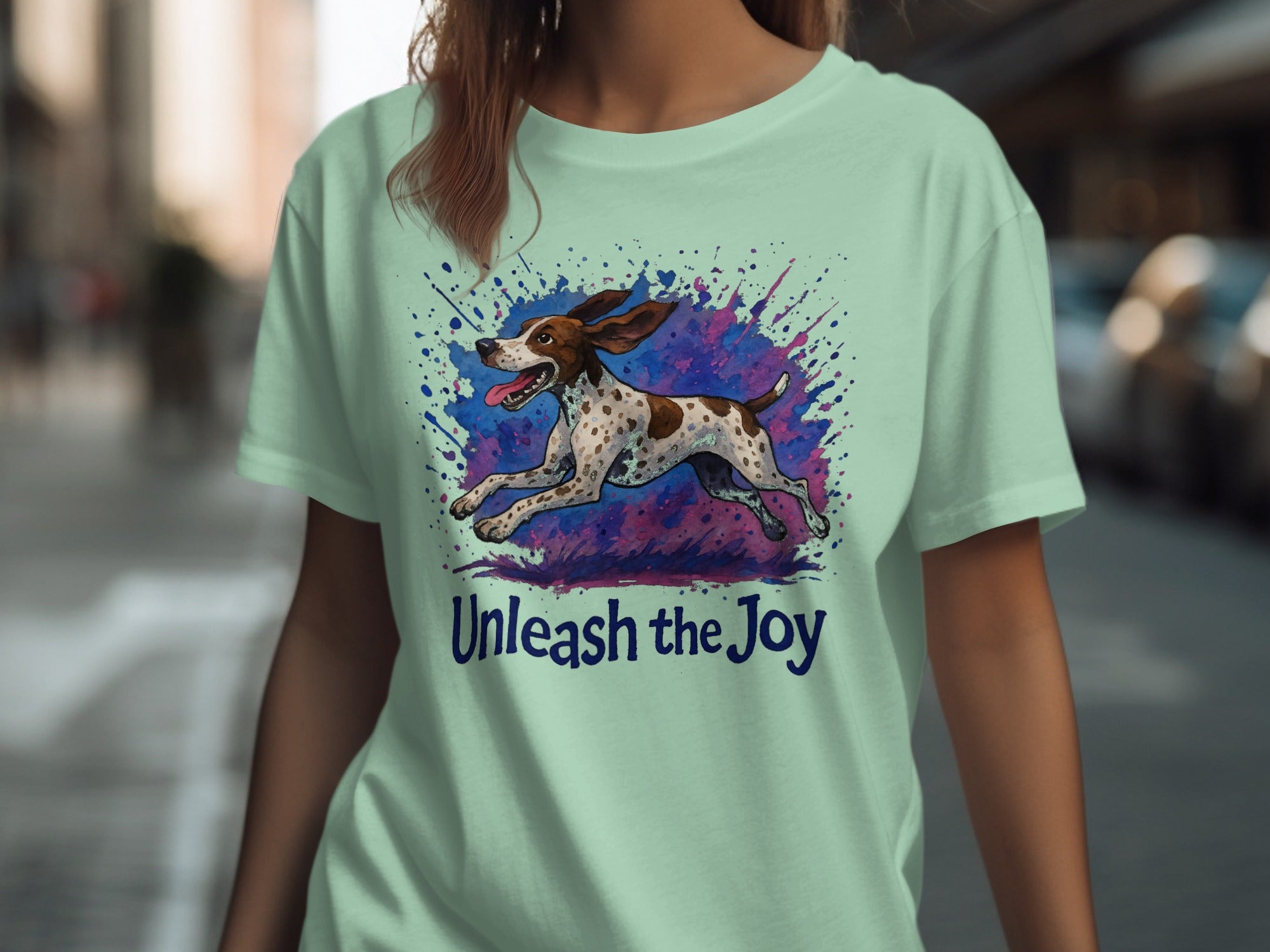 Light green t-shirt with a running dog illustration and "Unleash the Joy" text.