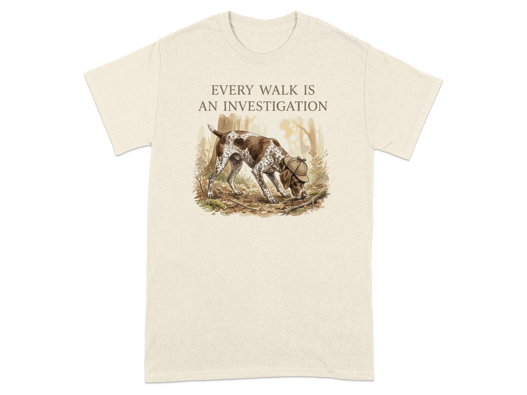 Beige t-shirt with a brown and white dog sniffing the ground in a forest.