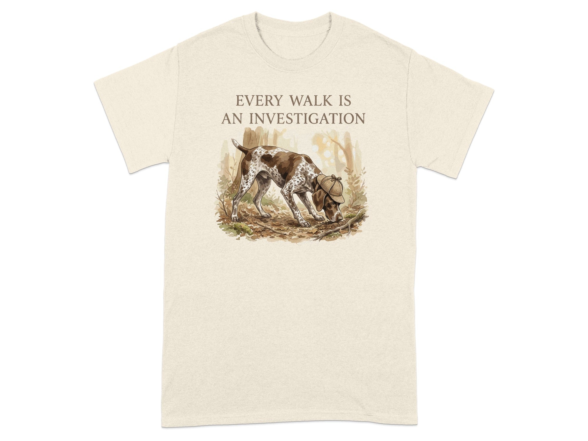 Beige t-shirt with a brown and white dog sniffing the ground in a forest.