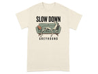 Cream t-shirt with a greyhound resting on a couch and "SLOW DOWN GREYHOUND" text.