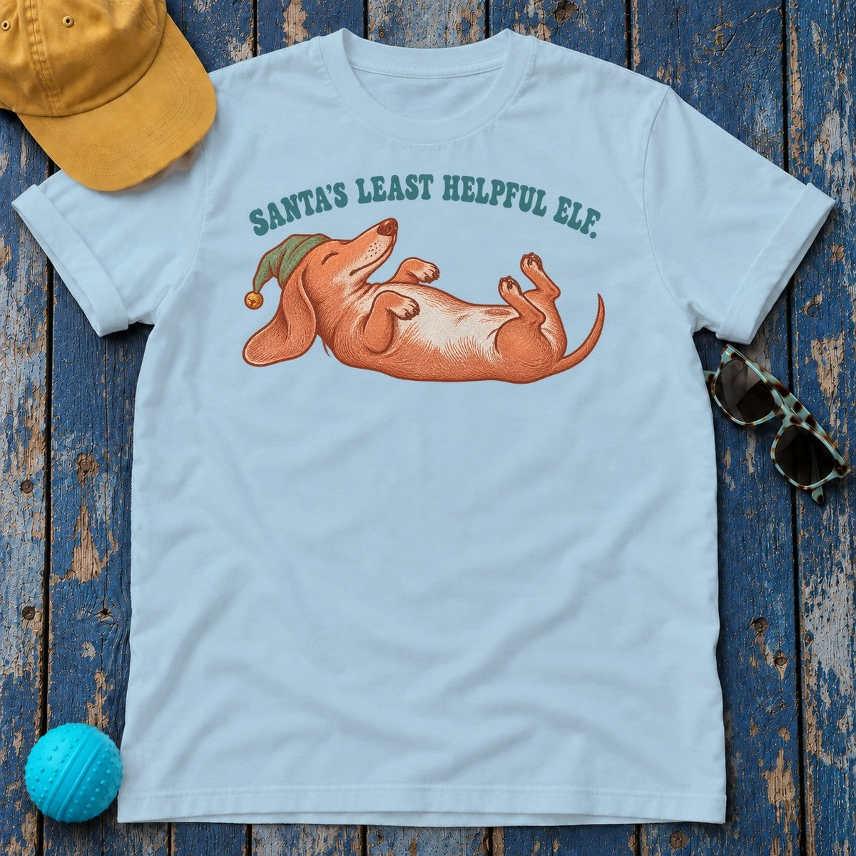 Santa's Least Helpful Elf Dachshund T-Shirt in Light Blue - flat lay