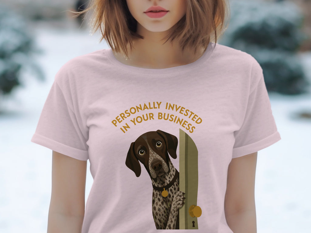 Pink t-shirt with a dog peeking from a door, text reads "PERSONALLY INVESTED IN YOUR BUSINESS".