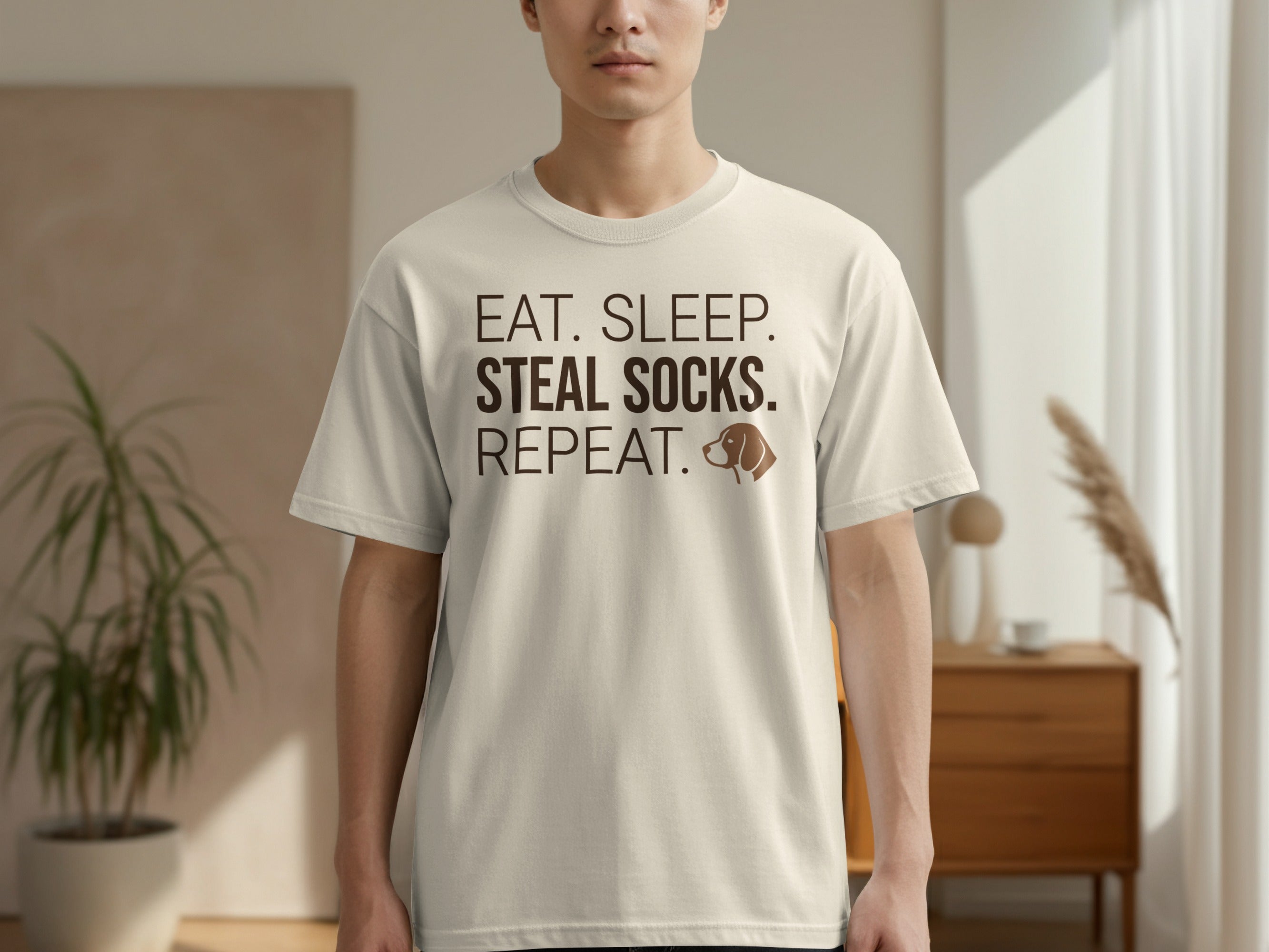 Cream t-shirt with text "EAT. SLEEP. STEAL SOCKS. REPEAT." and dog icon.