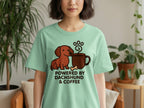 Mint green t-shirt with a cartoon dachshund and coffee cup graphic that reads "Powered by Dachshund & Coffee".
