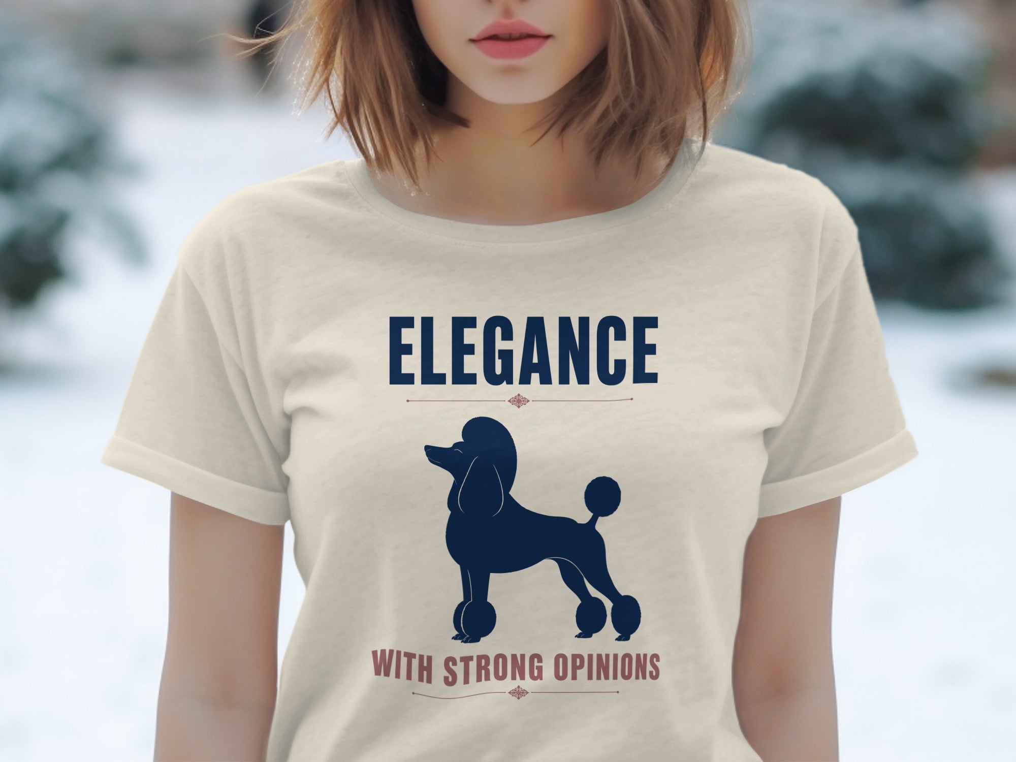 Cream t-shirt with navy poodle silhouette and "ELEGANCE WITH STRONG OPINIONS" text.