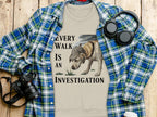 T-shirt with a dog in a hat, text "EVERY WALK IS AN INVESTIGATION."