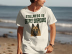 Cream t-shirt with a German Shepherd portrait and "STILLNESS IS DEEPLY SUSPICIOUS" text.