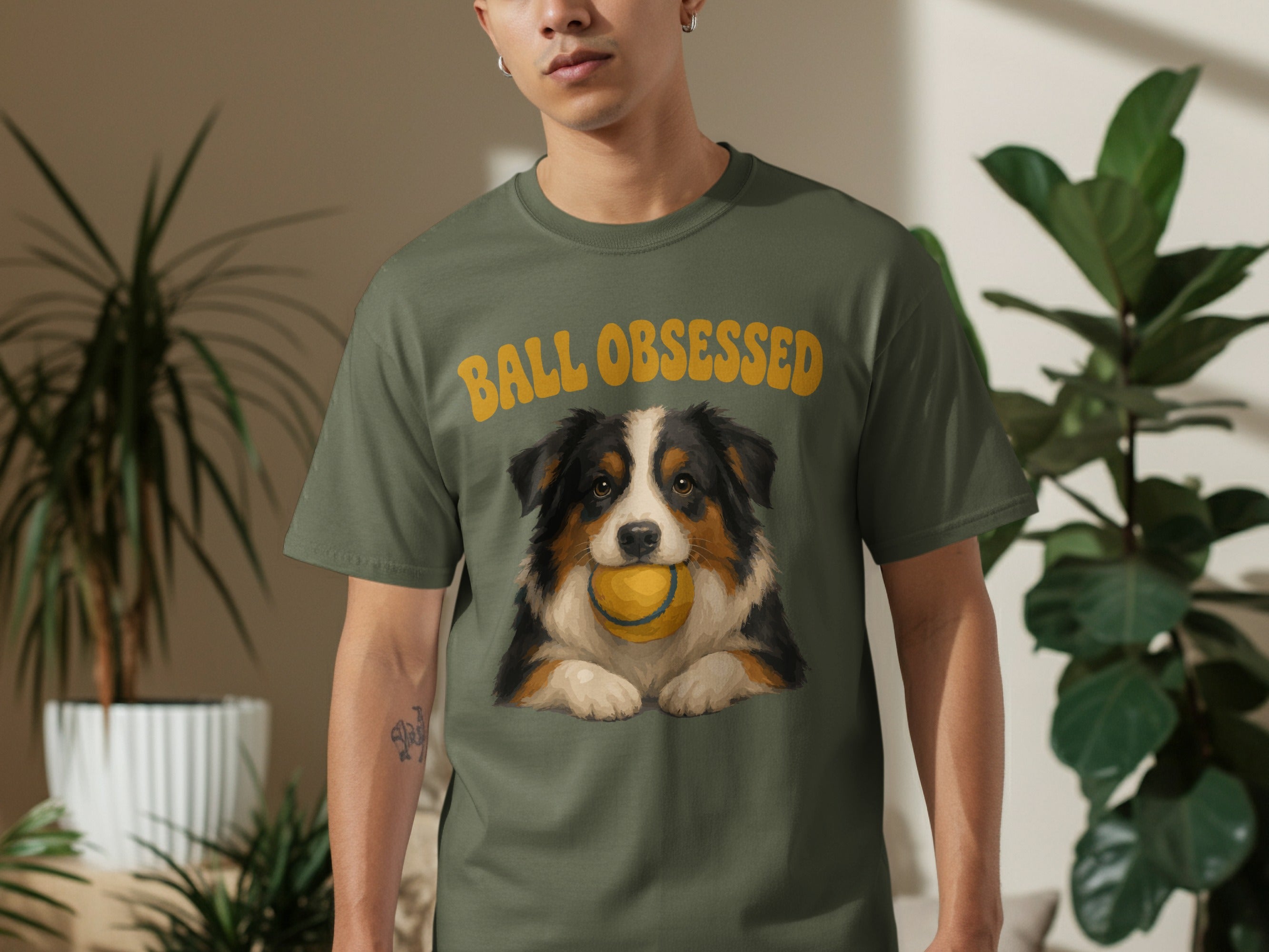 Man wearing green t-shirt with dog and "BALL OBSESSED" text.