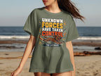Olive green t-shirt with "UNKNOWN FORCES HAVE TAKEN CONTROL THE ZOOMIES" graphic.
