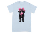 Black Labrador puppy with pink bow, sunglasses, and bubblegum on a light blue t-shirt.