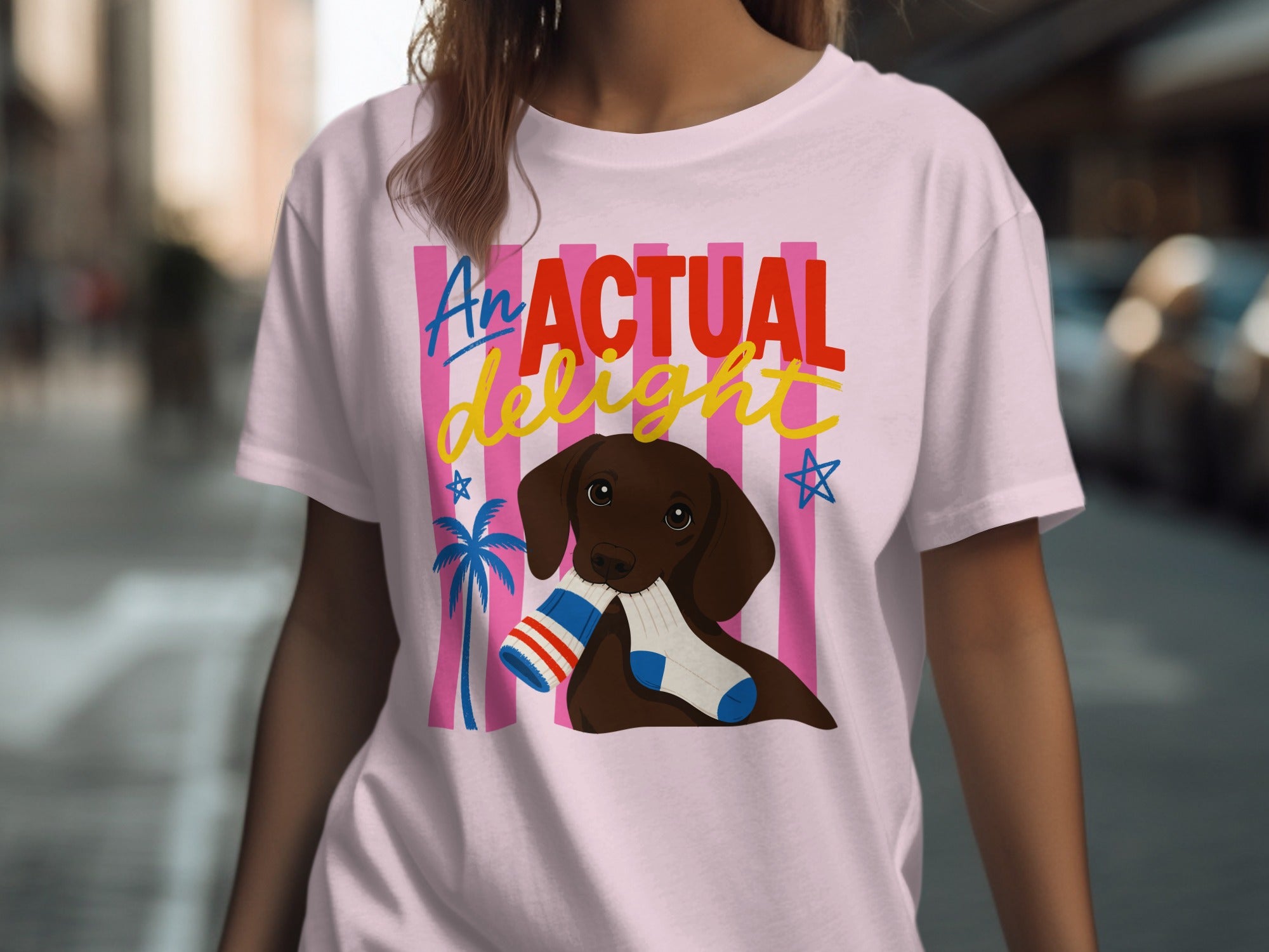 Pink t-shirt with "An actual delight" and a dog holding a sock.
