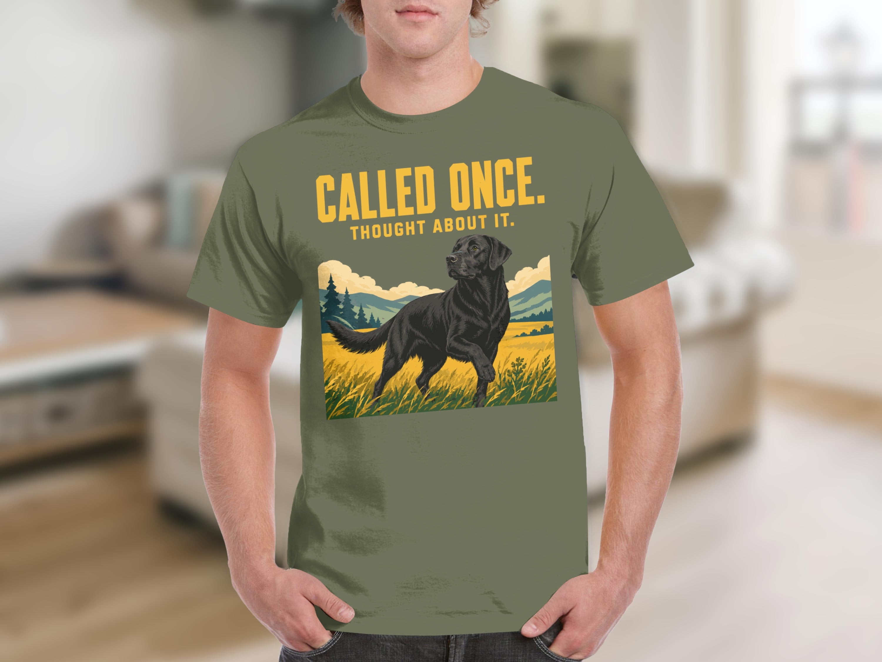 Olive green t-shirt featuring a black lab in a field with text "CALLED ONCE. THOUGHT ABOUT IT."