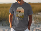 T-shirt graphic featuring a dog looking at a sunset over water, with text "Paws And Reflect".