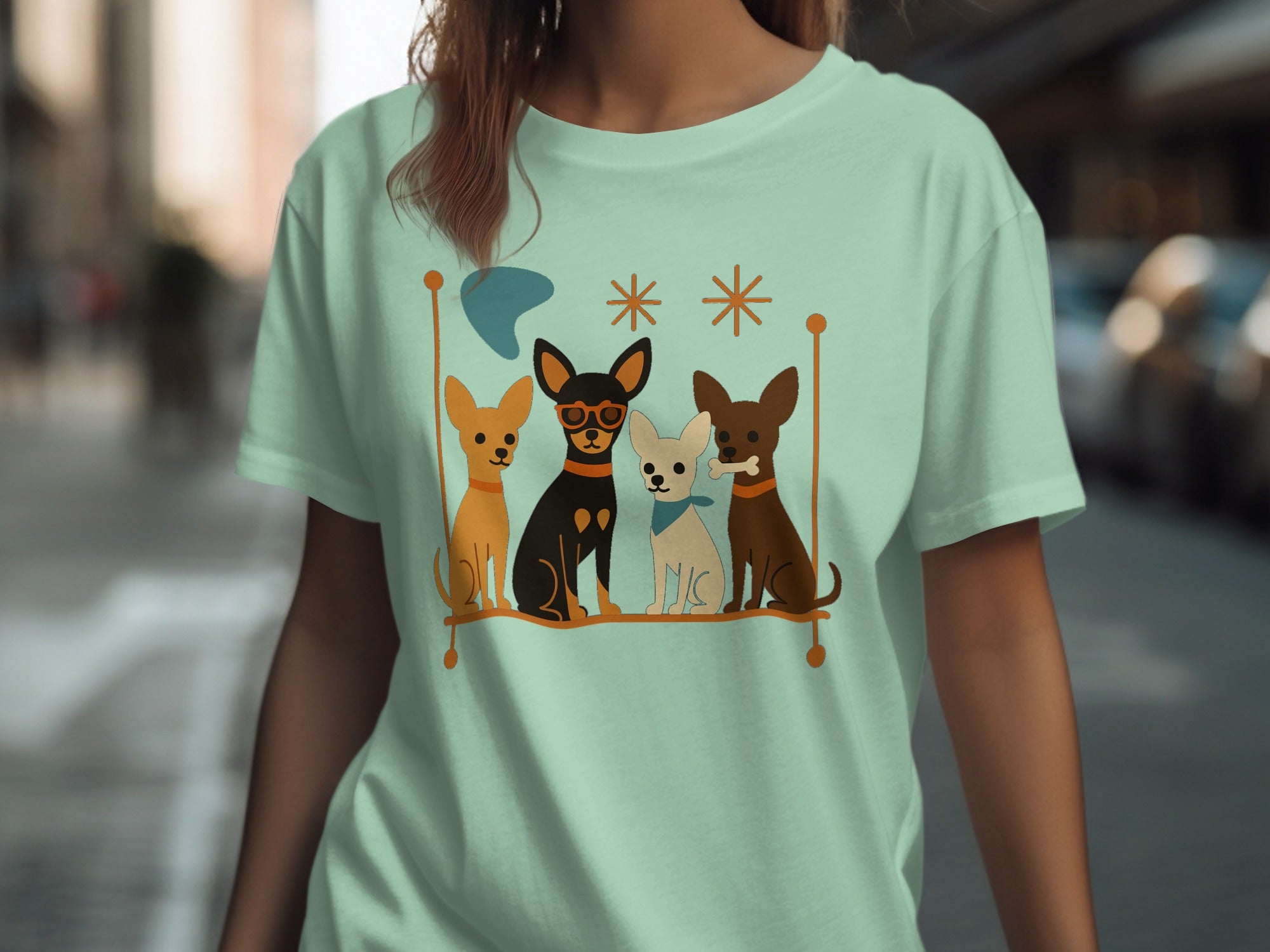 Four cartoon chihuahuas in a row on a pastel mint green t-shirt.