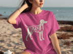 Pink t-shirt with white Vizsla dog silhouette and text on the beach.