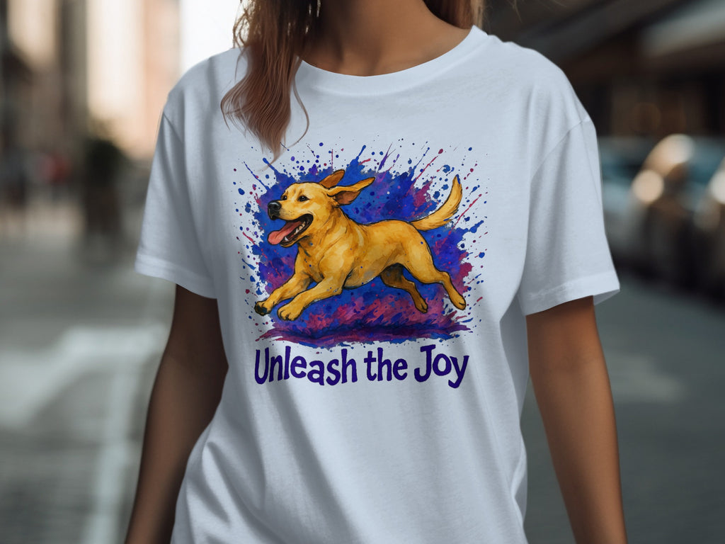 White t-shirt with a yellow dog in mid-stride, surrounded by a colorful splash, and text that reads "Unleash the Joy."