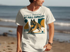 Man wearing a white t-shirt with a running dog and "Always Operating At Full Capacity" text.