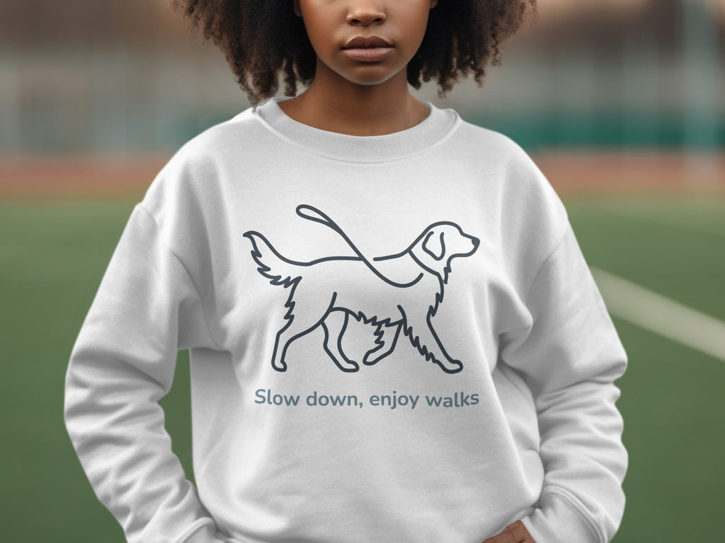 White sweatshirt with a line drawing of a dog on a leash and text "Slow down, enjoy walks".