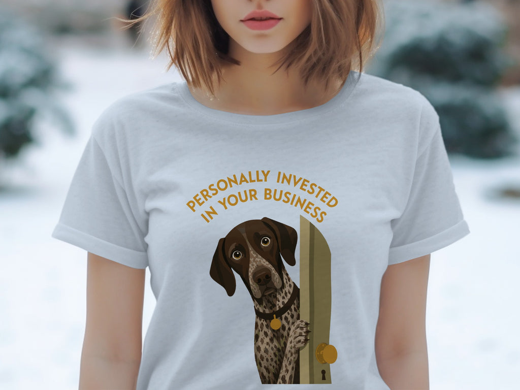 Woman wearing a light grey t-shirt with a dog peeking through a doorway.