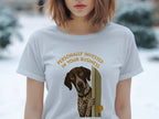 Woman wearing a light grey t-shirt with a dog peeking through a doorway.