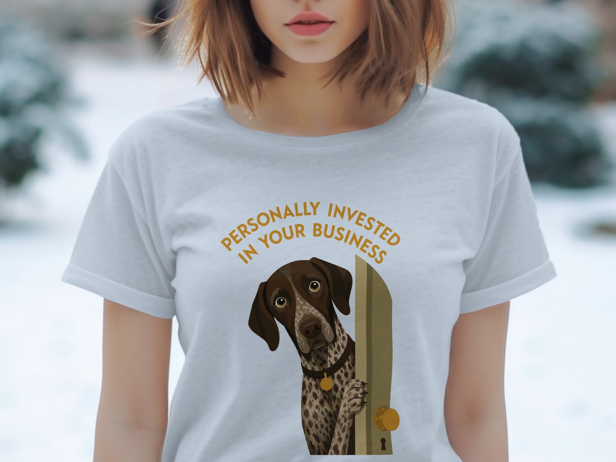 Woman wearing a light grey t-shirt with a dog peeking through a doorway.