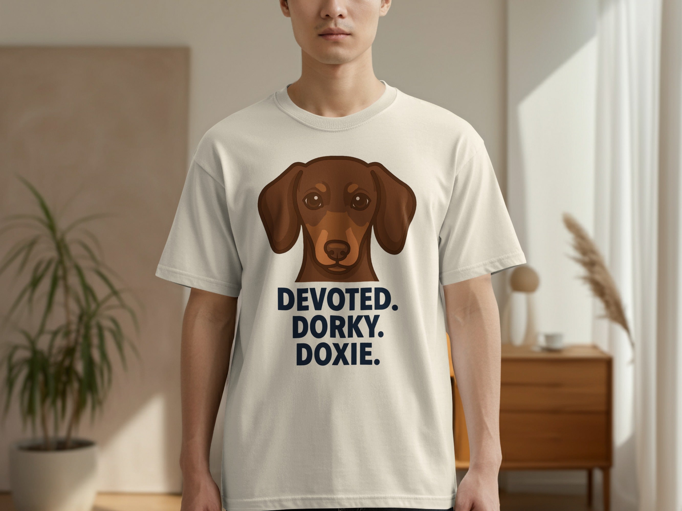Cream t-shirt with a dachshund illustration and text "DEVOTED. DORKY. DOXIE."