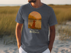 T-shirt with a graphic of a dog by a lake at sunset and text "Paws And Reflect".