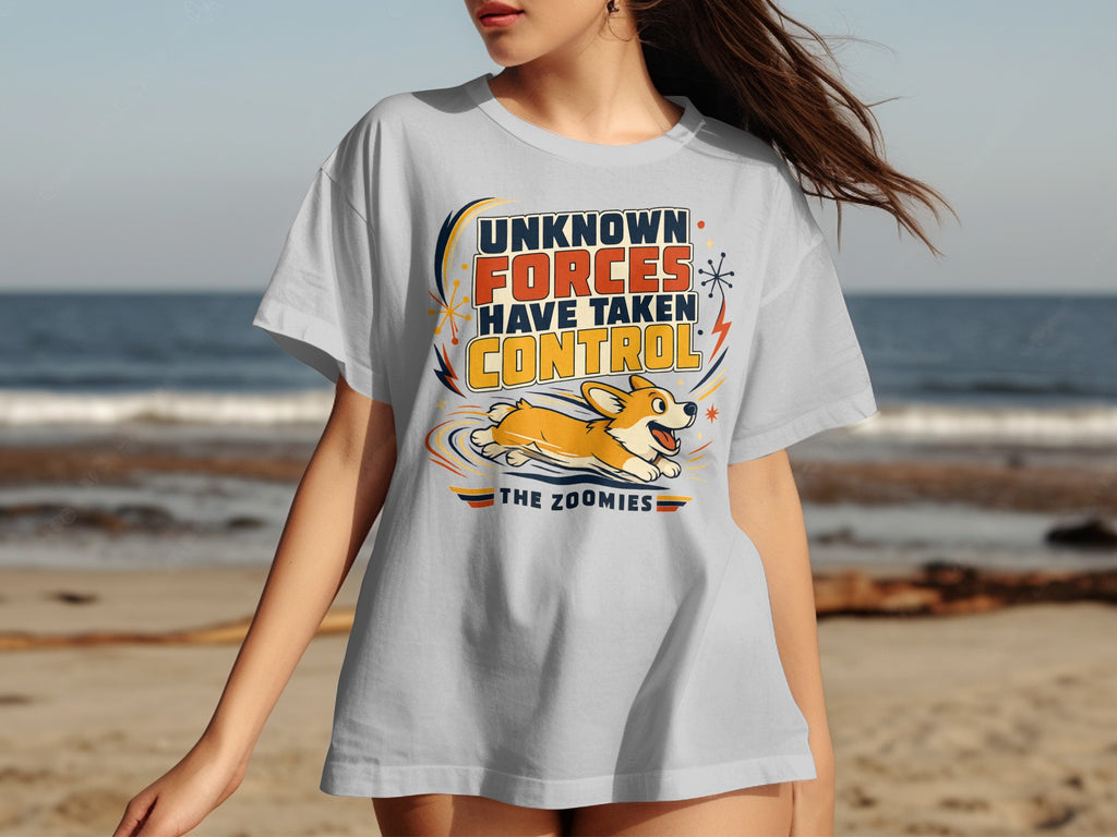 White t-shirt with cartoon corgi and text "UNKNOWN FORCES HAVE TAKEN CONTROL THE ZOOMIES".