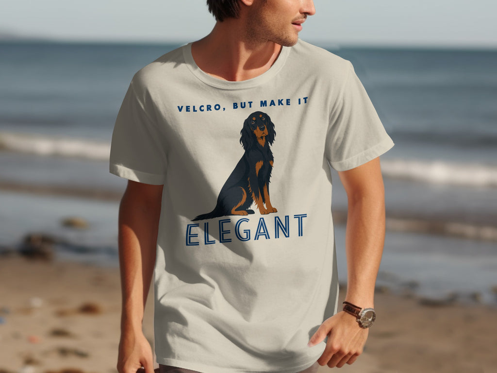 Man wearing tan t-shirt with dog graphic and "VELCRO, BUT MAKE IT ELEGANT" text.