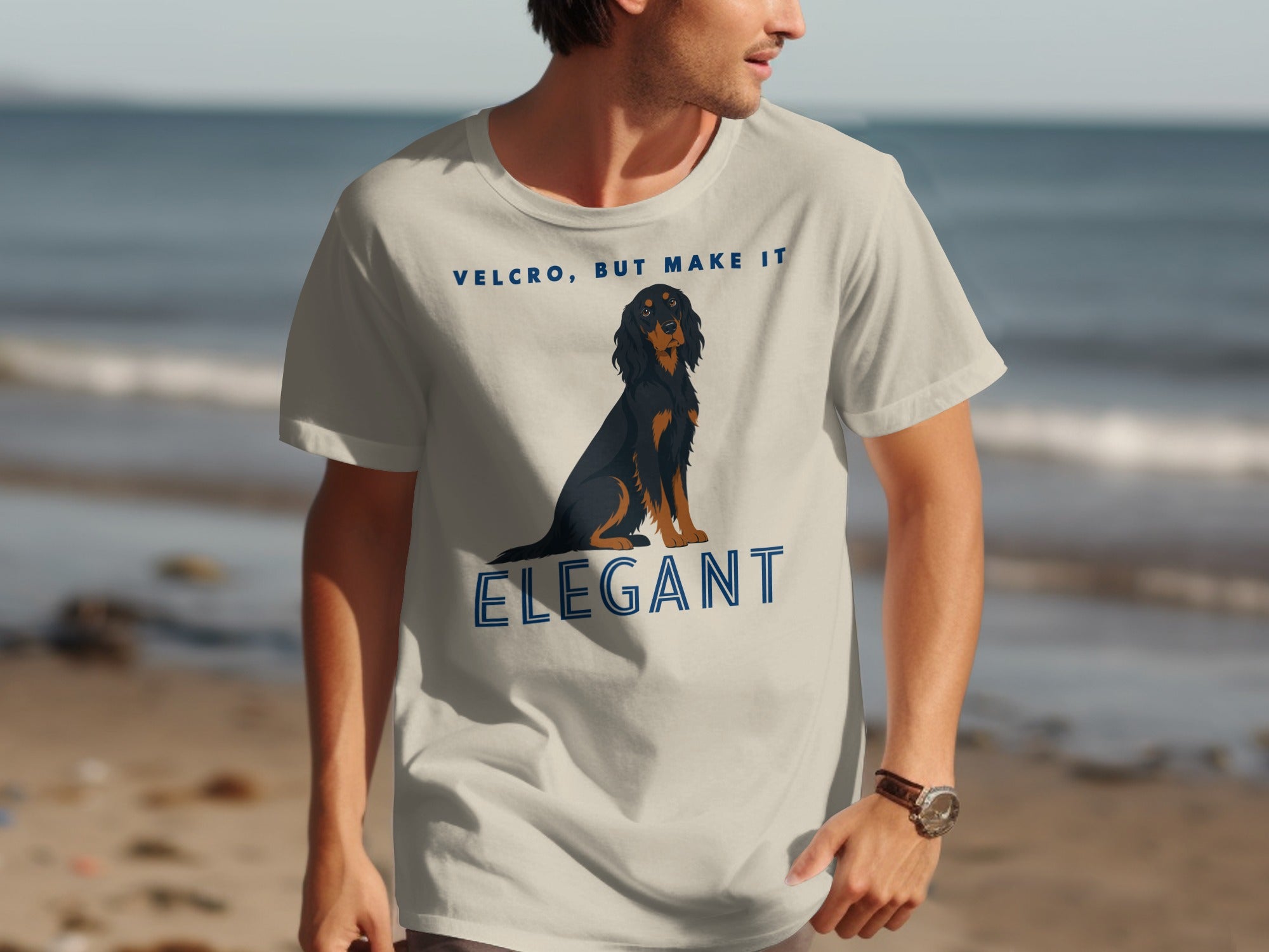 Man wearing tan t-shirt with dog graphic and "VELCRO, BUT MAKE IT ELEGANT" text.