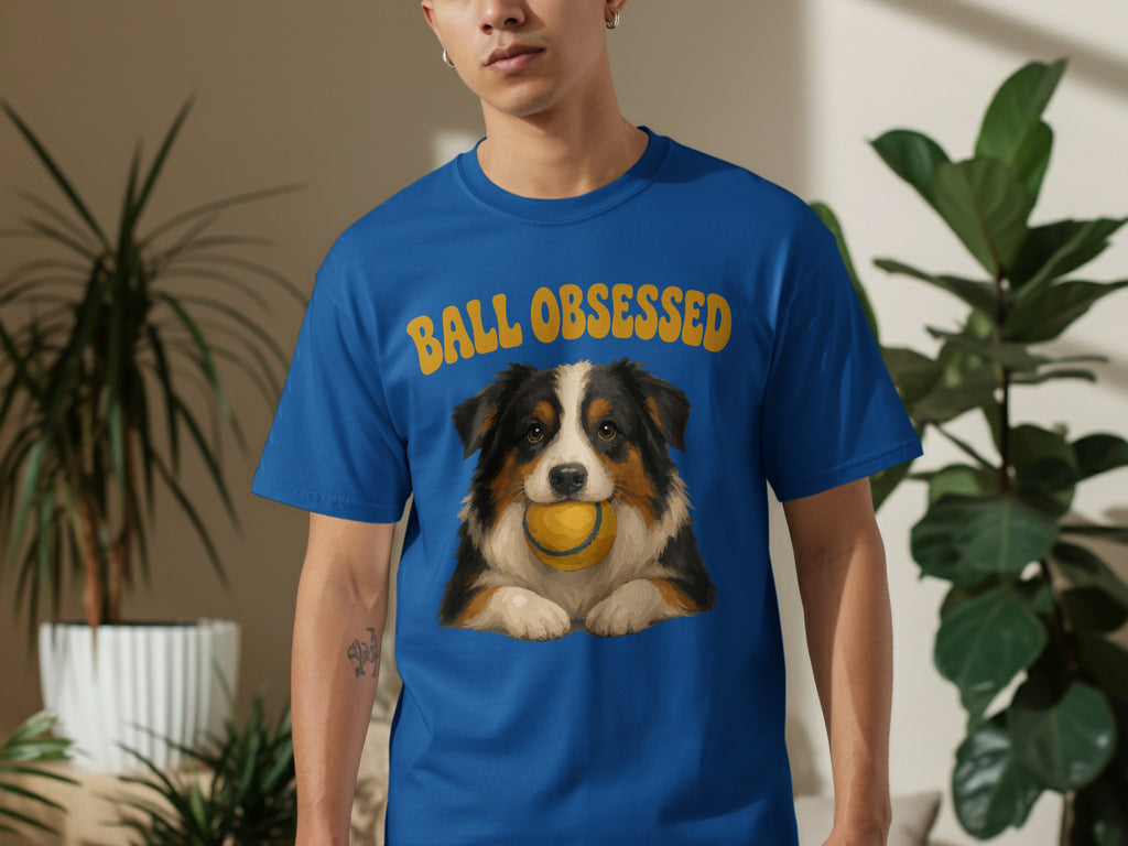 Blue t-shirt with a dog holding a tennis ball and text "Ball obsessed".