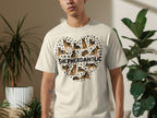 Cream t-shirt with heart-shaped collage of various shepherd dog illustrations and paw prints.