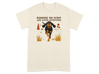 Cream t-shirt with illustration of a black and tan dog running, text reads "RUNNING ON SCENT AND GOOD INTENTIONS".
