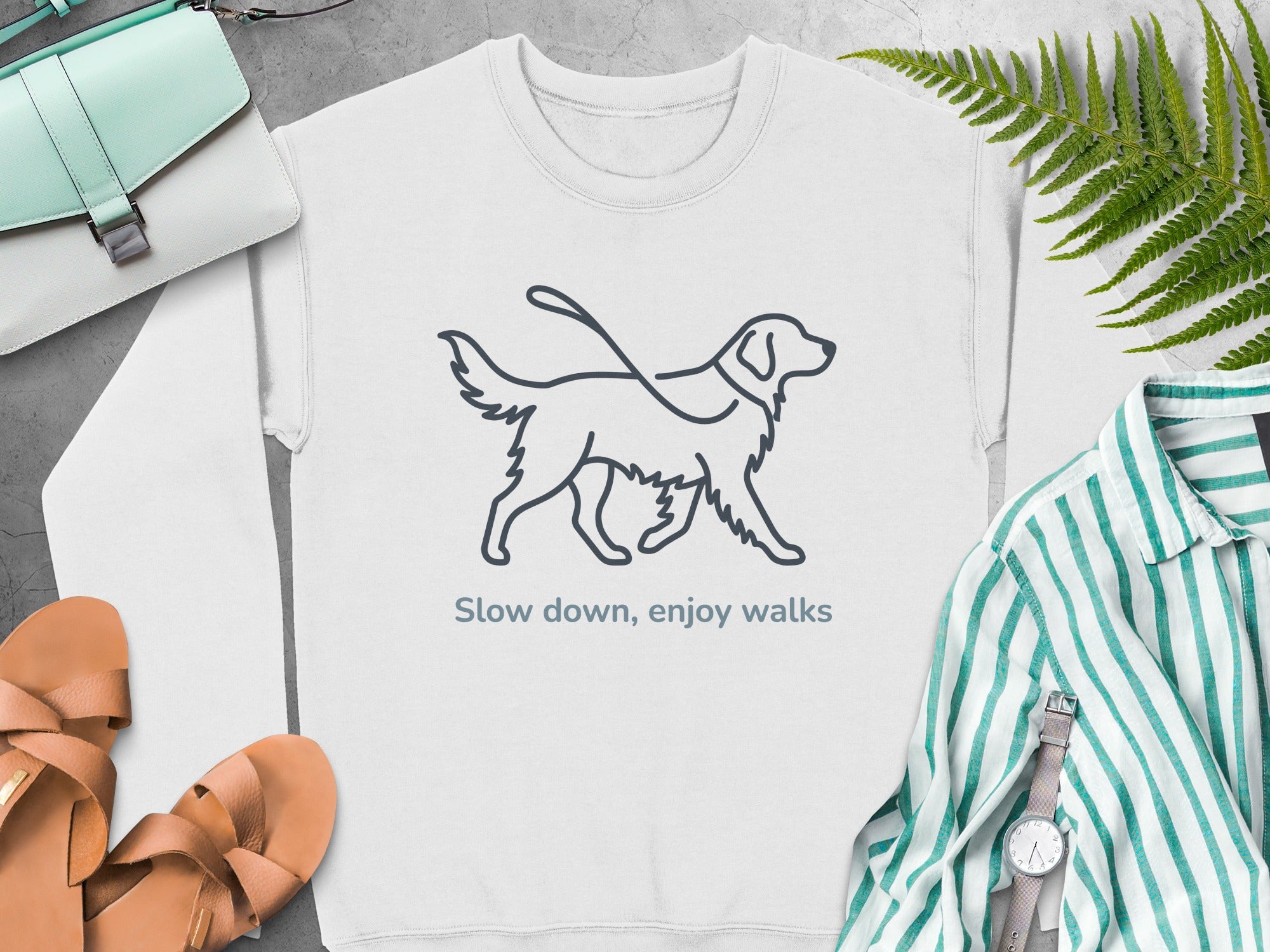 Crewneck sweatshirt with a line drawing of a dog on a leash and the text "Slow down, enjoy walks".