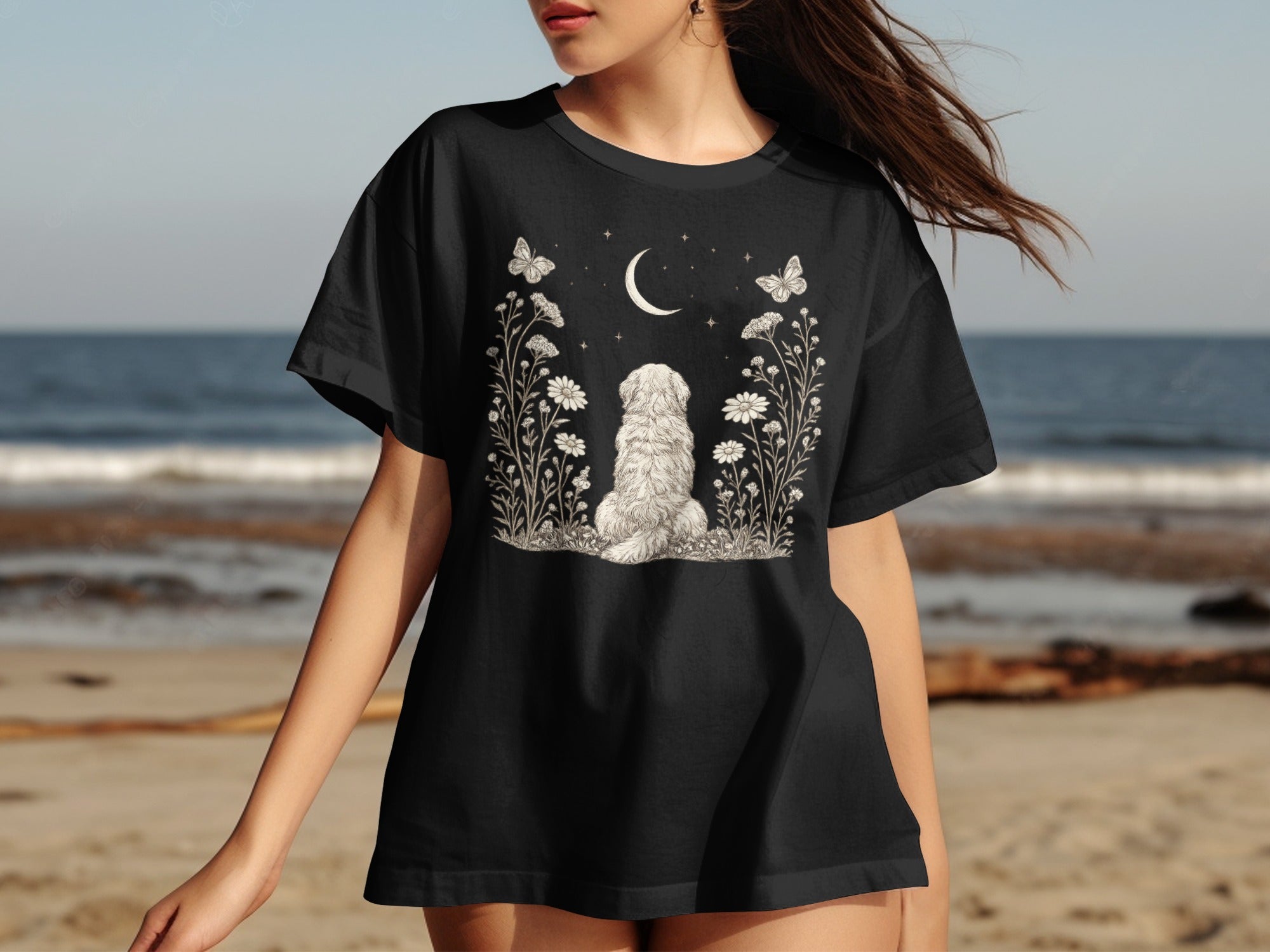 Black t-shirt with a drawing of a fluffy dog sitting amongst flowers under a crescent moon.