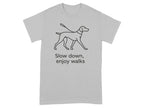 Grey t-shirt with black line drawing of a dog on a leash and text "Slow down, enjoy walks".