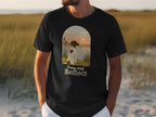 Black t-shirt with a dog looking at a sunset over water, text "Paws and Reflect."
